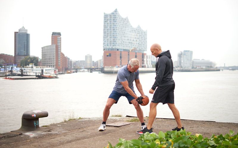Henrik Schünemann begleitet einen Kunden bei einer Medizinball-Übung am Hamburger Hafen